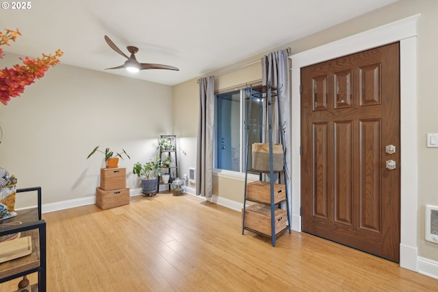 entryway featuring light wood-type flooring, a ceiling fan, baseboards, and arched walkways