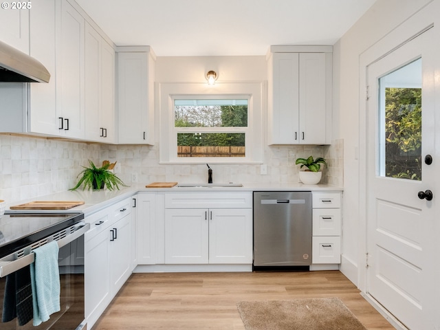 kitchen featuring appliances with stainless steel finishes, ventilation hood, sink, white cabinets, and light hardwood / wood-style floors