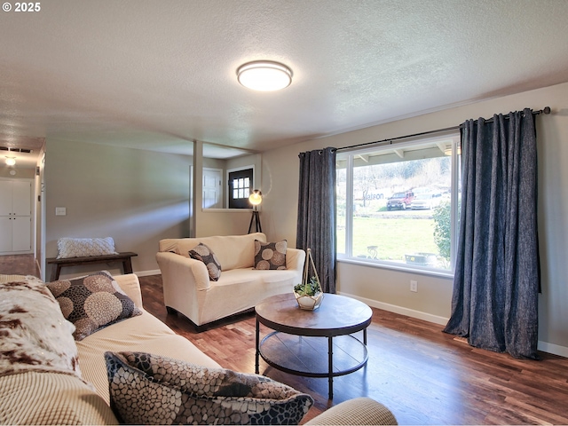 living area with baseboards, a textured ceiling, wood finished floors, and visible vents
