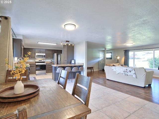 dining area featuring light tile patterned flooring, a textured ceiling, and baseboards