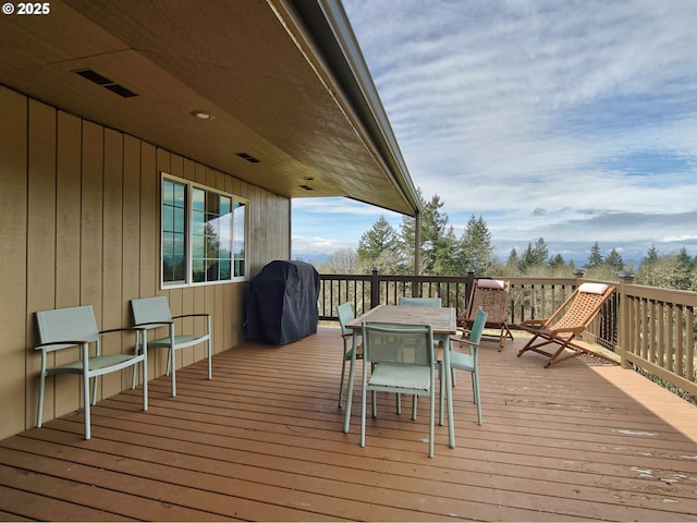 wooden terrace featuring visible vents, outdoor dining space, and a grill