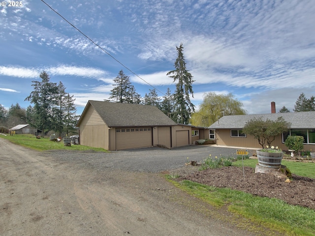 view of front of property featuring a chimney, an outbuilding, and driveway