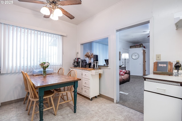 dining space featuring light carpet and ceiling fan