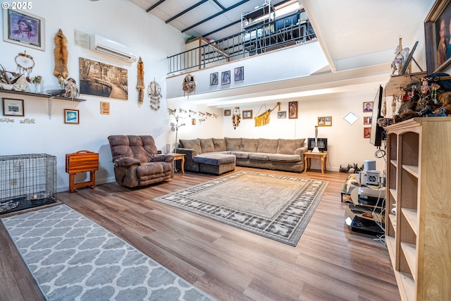 living room featuring a wall mounted air conditioner, hardwood / wood-style flooring, and a towering ceiling