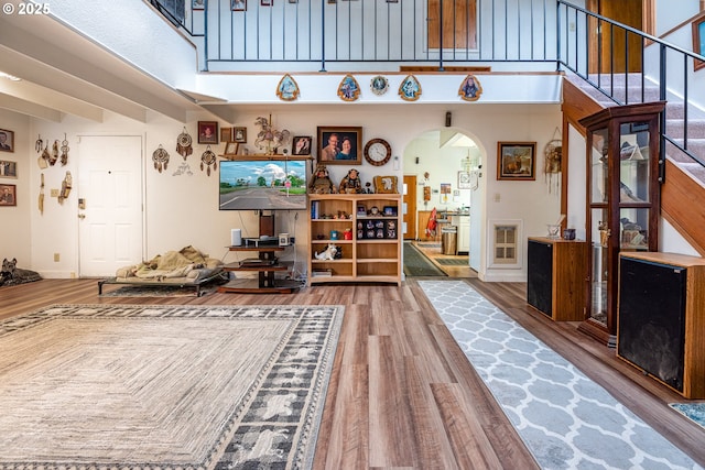 living room featuring beamed ceiling, wood-type flooring, and a high ceiling