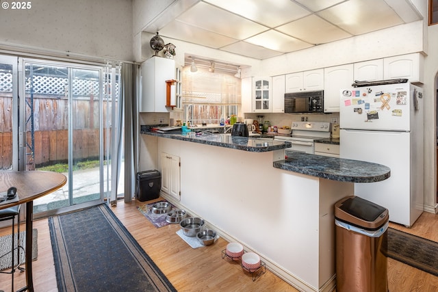 kitchen with white cabinetry, white appliances, a healthy amount of sunlight, and light hardwood / wood-style floors