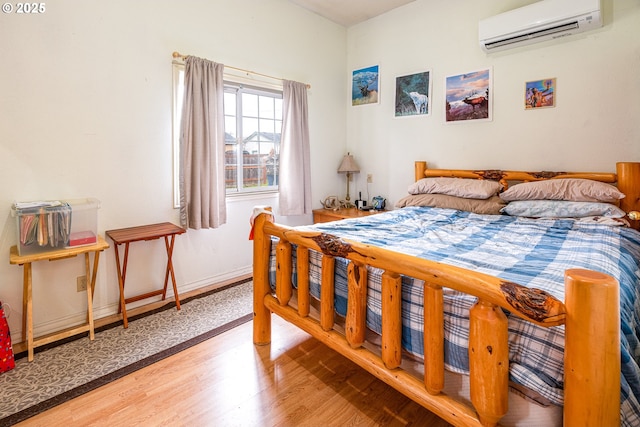 bedroom featuring a wall mounted air conditioner and hardwood / wood-style flooring