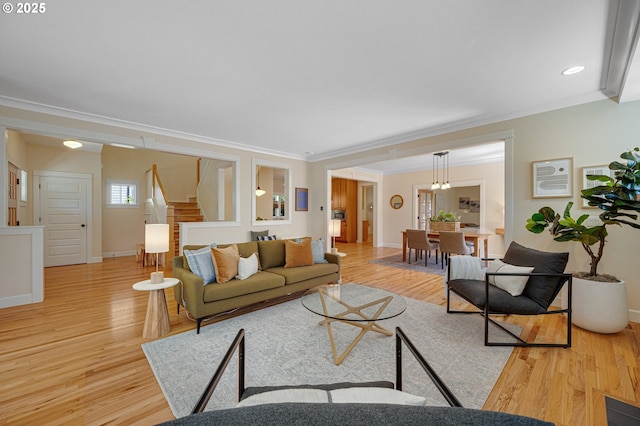 living area with crown molding, baseboards, light wood finished floors, and stairway