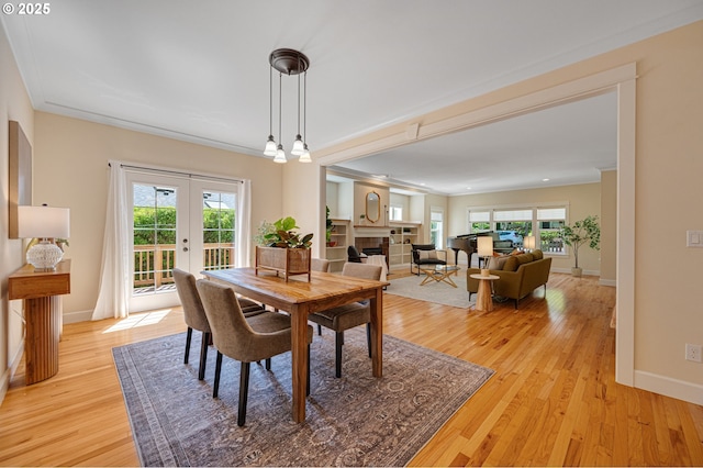 dining area featuring light wood-style floors, french doors, plenty of natural light, and ornamental molding