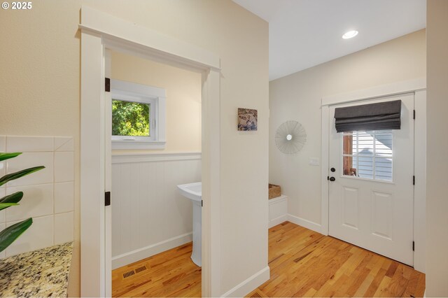 entrance foyer with light wood-style flooring, a wainscoted wall, and baseboards