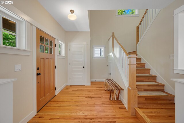 entryway featuring light wood finished floors, stairs, and baseboards