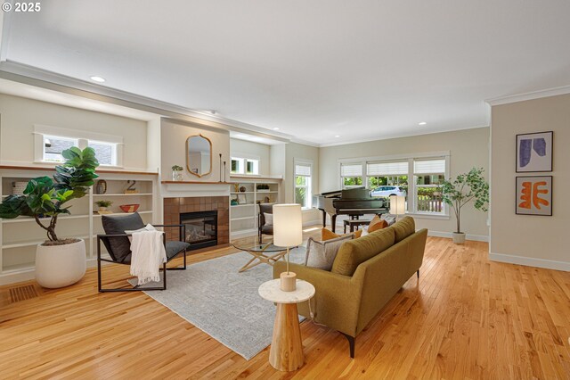 living area with ornamental molding, wood finished floors, recessed lighting, a tiled fireplace, and baseboards