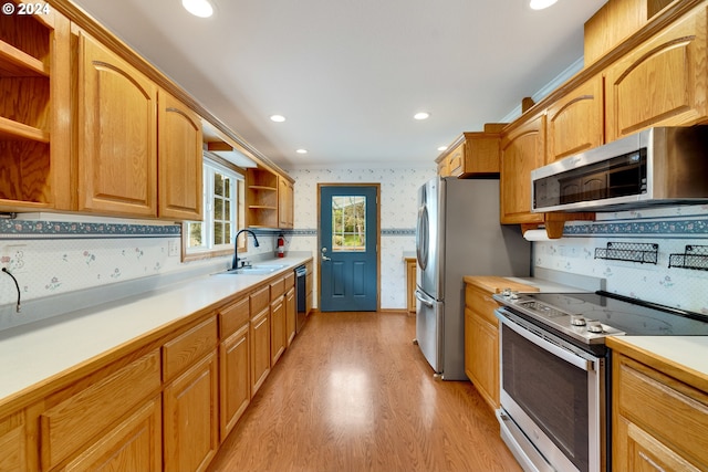 kitchen featuring backsplash, sink, stainless steel appliances, and light hardwood / wood-style flooring