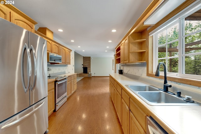 kitchen featuring appliances with stainless steel finishes, light wood-type flooring, tasteful backsplash, sink, and light brown cabinets