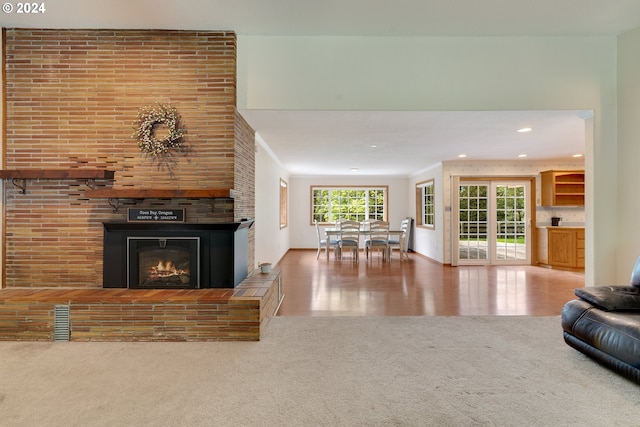 unfurnished living room featuring crown molding, a large fireplace, and carpet floors