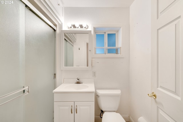 bathroom with a shower with door, vanity, and toilet