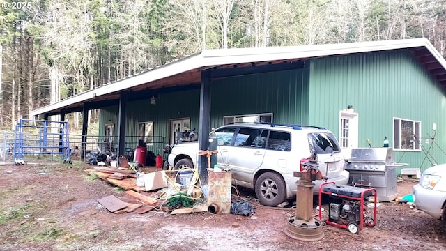 view of outdoor structure with a carport, an outbuilding, and a forest view