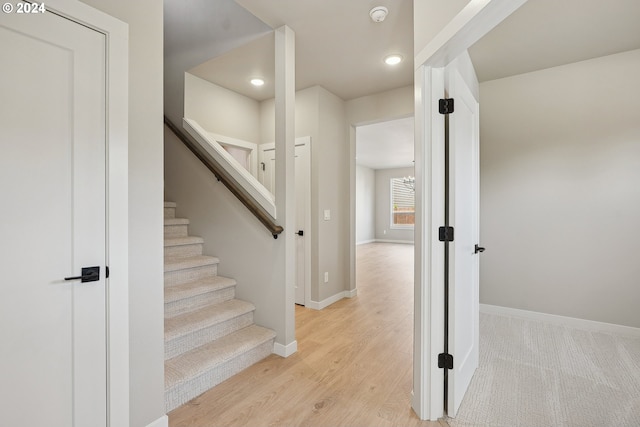 stairway featuring hardwood / wood-style floors and an inviting chandelier