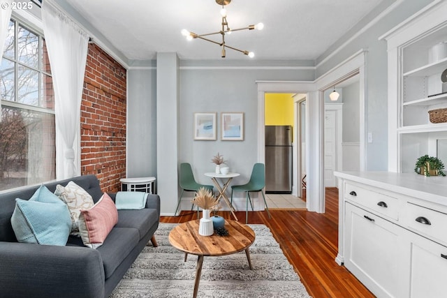 living area with an inviting chandelier, brick wall, and dark hardwood / wood-style floors