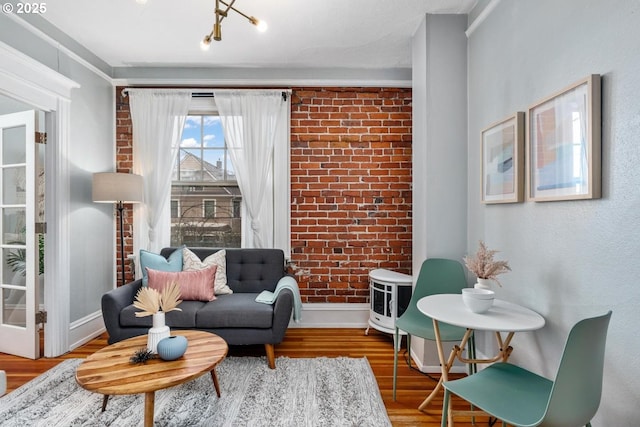 living area featuring brick wall and wood-type flooring