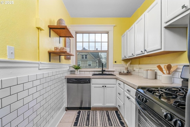 kitchen with white cabinetry, dishwasher, sink, black range with gas stovetop, and light tile patterned floors