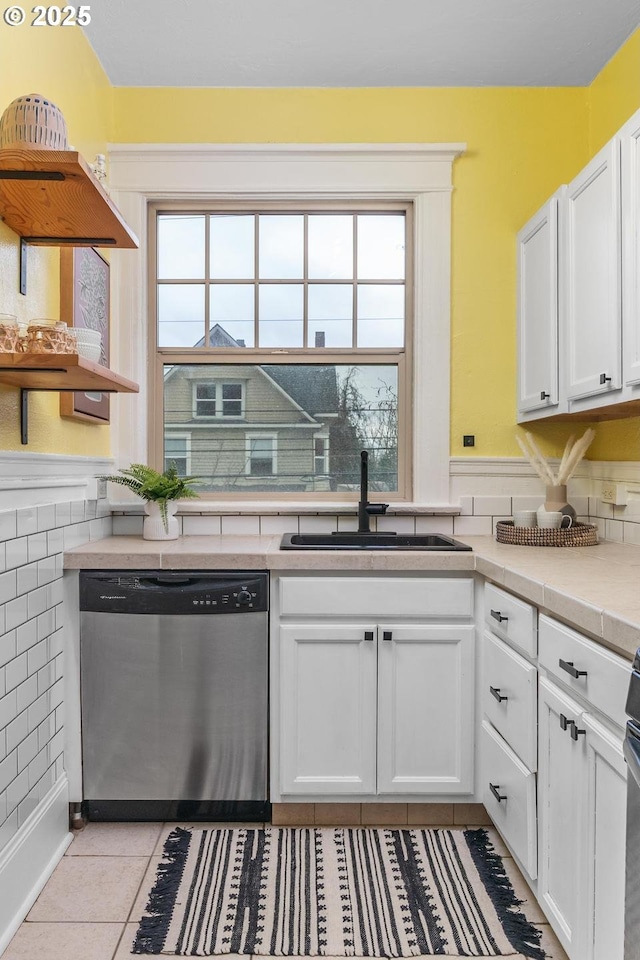 kitchen with stainless steel dishwasher, a wealth of natural light, sink, and white cabinets