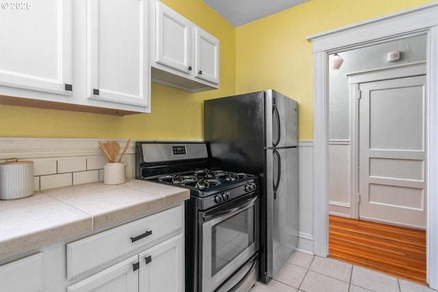 kitchen featuring gas range, white cabinetry, and light tile patterned floors