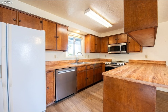 4631 Daisy St, Springfield, OR 97478 - kitchen with stainless steel appliances, a peninsula, light wood finished floors, brown cabinets, and a textured ceiling