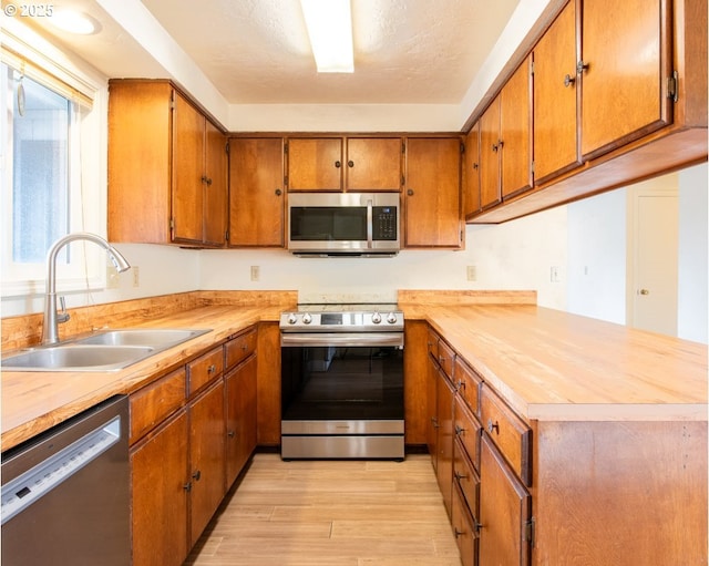 4631 Daisy St, Springfield, OR 97478 - kitchen featuring stainless steel appliances, light wood finished floors, brown cabinetry, and light countertops