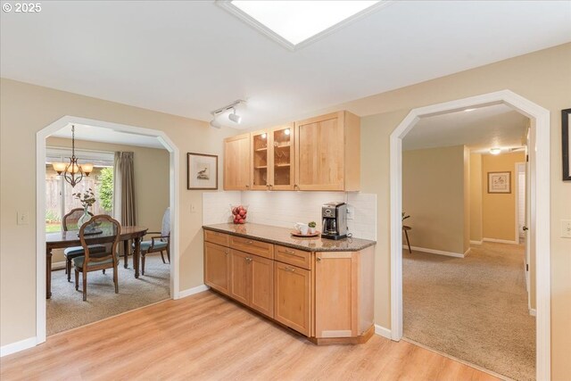 8740 SW Bomar Ct, Portland, OR 97223 - kitchen featuring arched walkways, glass insert cabinets, a chandelier, backsplash, and light stone countertops