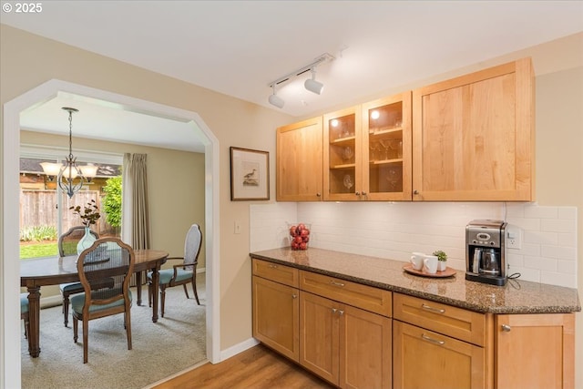 8740 SW Bomar Ct, Portland, OR 97223 - kitchen featuring a chandelier, glass insert cabinets, dark stone countertops, decorative backsplash, and arched walkways