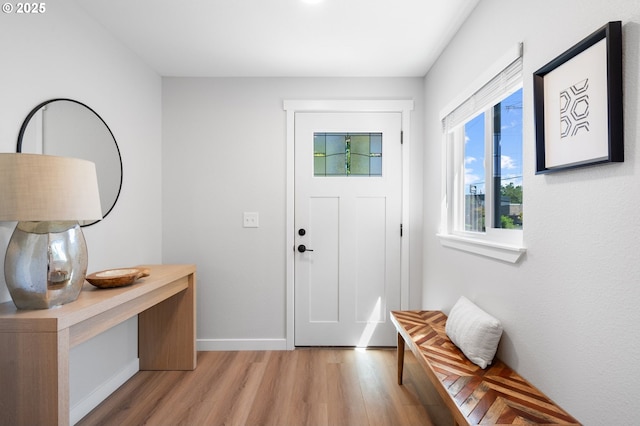 doorway featuring light wood finished floors and baseboards
