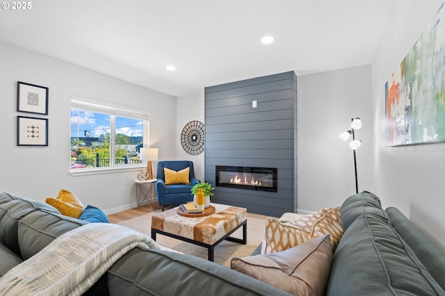 living room featuring a fireplace, recessed lighting, baseboards, and wood finished floors