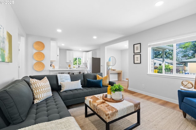 living area featuring baseboards, light wood finished floors, and recessed lighting