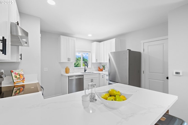 kitchen with a sink, a peninsula, stainless steel appliances, white cabinetry, and range hood