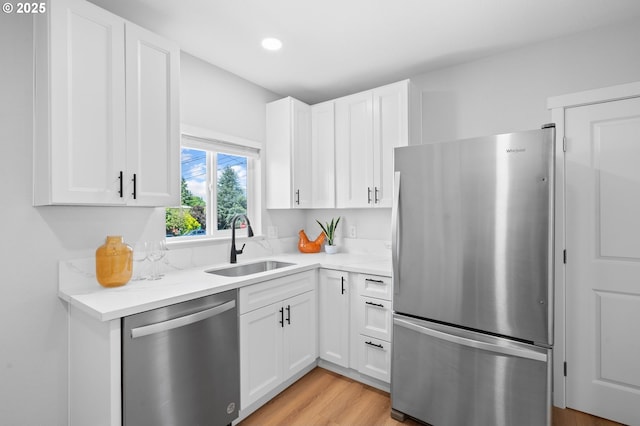 kitchen featuring a sink, recessed lighting, light wood finished floors, white cabinets, and appliances with stainless steel finishes