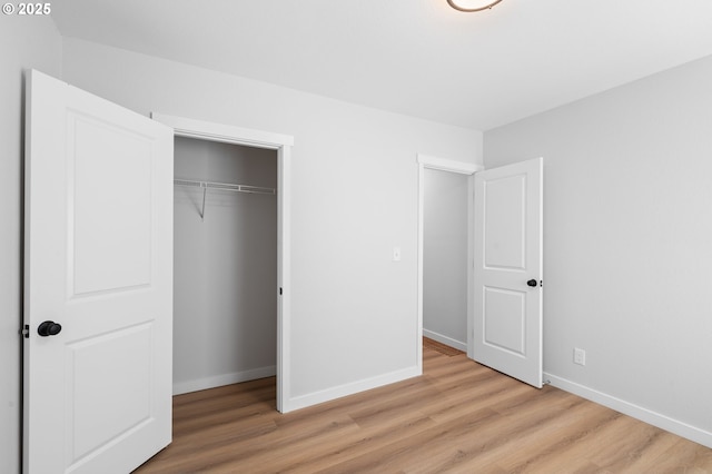 unfurnished bedroom with baseboards, light wood-style floors, and a closet