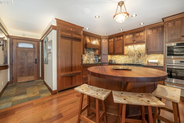 1 3rd St Unit 501, Astoria, OR 97103 - kitchen featuring wood counters, custom exhaust hood, backsplash, stainless steel double oven, and recessed lighting