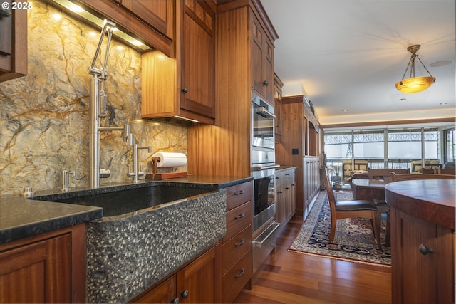 1 3rd St Unit 501, Astoria, OR 97103 - kitchen featuring dark wood-style flooring, backsplash, brown cabinets, a warming drawer, and hanging light fixtures
