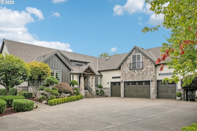 view of front facade with driveway, stone siding, board and batten siding, and an attached garage