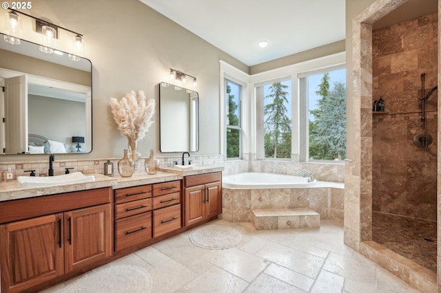 bathroom featuring a garden tub, double vanity, a tile shower, stone tile flooring, and decorative backsplash
