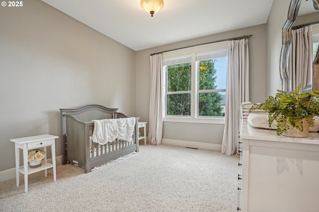 carpeted bedroom featuring baseboards and a crib
