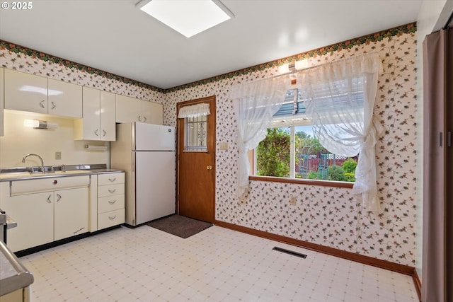 1550 Ash St, Baker City, OR 97814 - kitchen with freestanding refrigerator, cream cabinetry, a sink, wallpapered walls, and baseboards