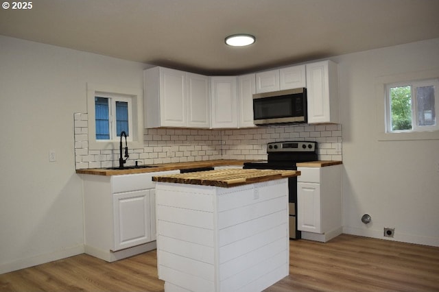 kitchen featuring a center island, appliances with stainless steel finishes, white cabinets, sink, and butcher block countertops