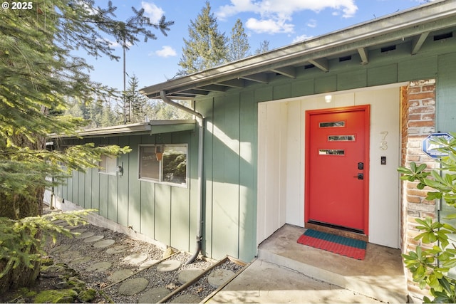 view of exterior entry with brick siding and board and batten siding