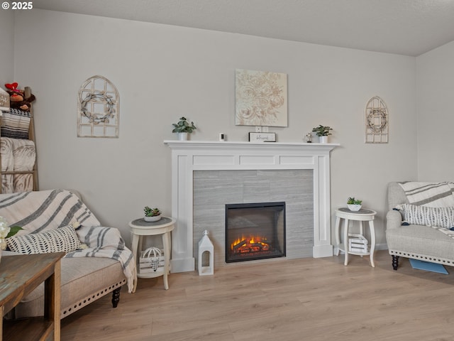 sitting room featuring a tile fireplace and light wood-style floors