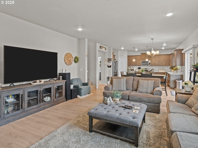 living area with recessed lighting, a notable chandelier, light wood-style flooring, and a textured ceiling