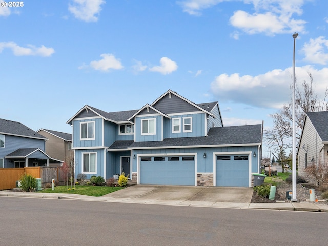 view of front of house with an attached garage, board and batten siding, fence, stone siding, and driveway