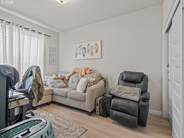 living area with baseboards, light wood-style floors, and a textured ceiling