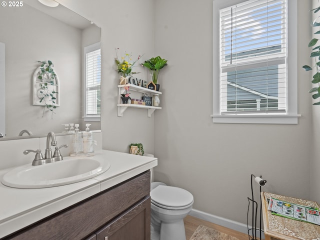 bathroom with vanity, toilet, wood finished floors, and baseboards